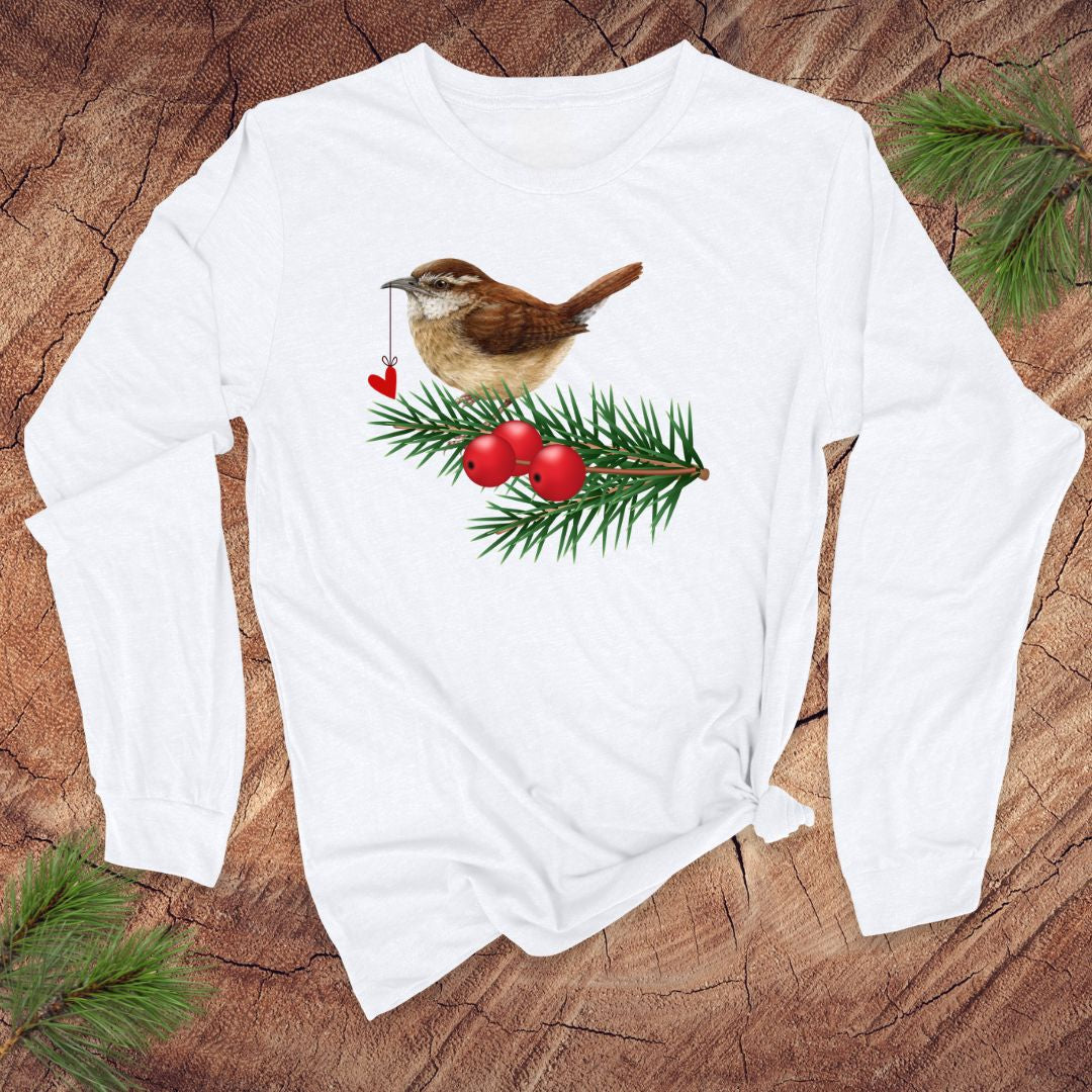 White long-sleeve shirt with a Christmas-themed design featuring a bird, berries, and pine branches on a wooden surface.