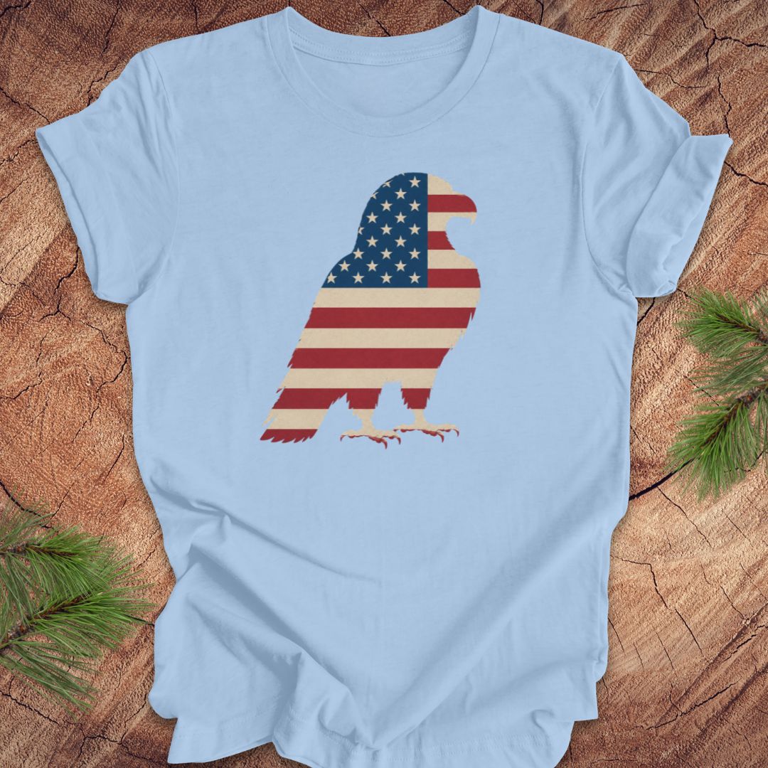 Light blue t-shirt with a graphic of an eagle in American flag design on a wooden surface.