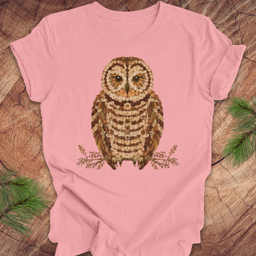 Pink t-shirt with an owl and flower design on a wooden surface