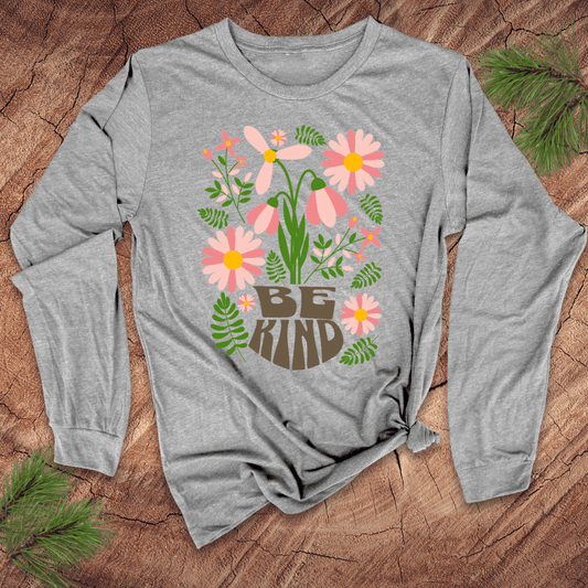 Gray long-sleeve shirt with floral design and 'Be Kind' text on a wooden surface