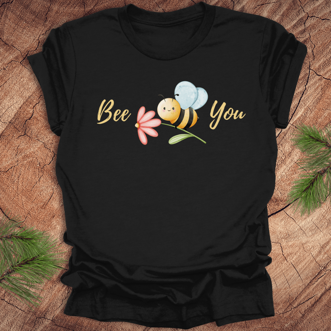 Black tshirt with a cute bee and the text, "bee you" on a wooden background.