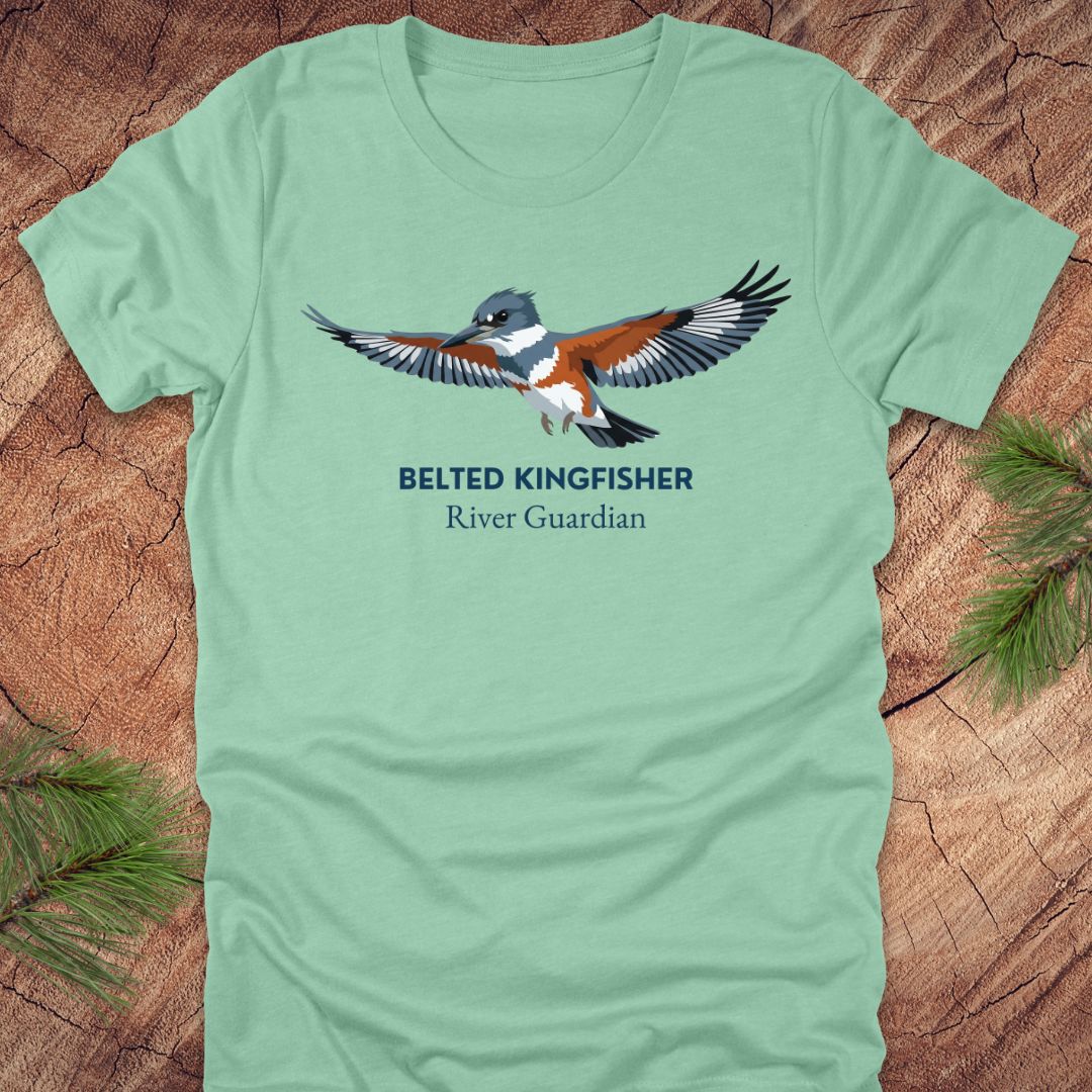 Mint green t-shirt with belted kingfisher design and text, 'belted kingfisher river guardian'on a wooden surface