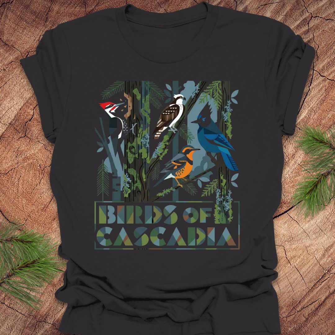 Dark gray t-shirt with colorful bird design and 'Birds of Cascadia' text on a wooden surface.