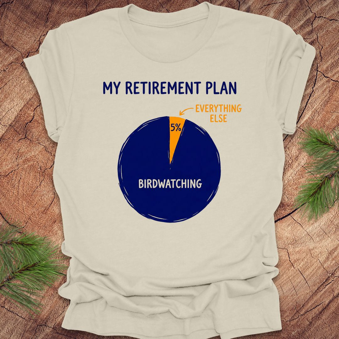 Beige t-shirt with a birdwatching retirement plan pie chart design on a wooden surface