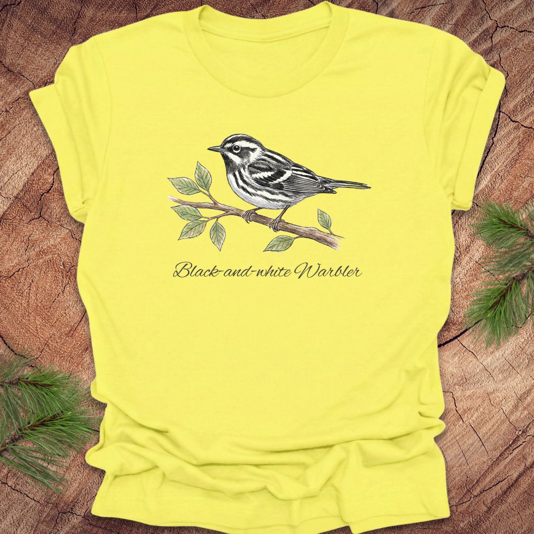Yellow t-shirt with a black and white warbler design on a wooden surface