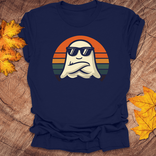 Navy blue t-shirt with a graphic of a ghost wearing sunglasses and a colorful sunset in the background, placed on a wooden surface with autumn leaves.