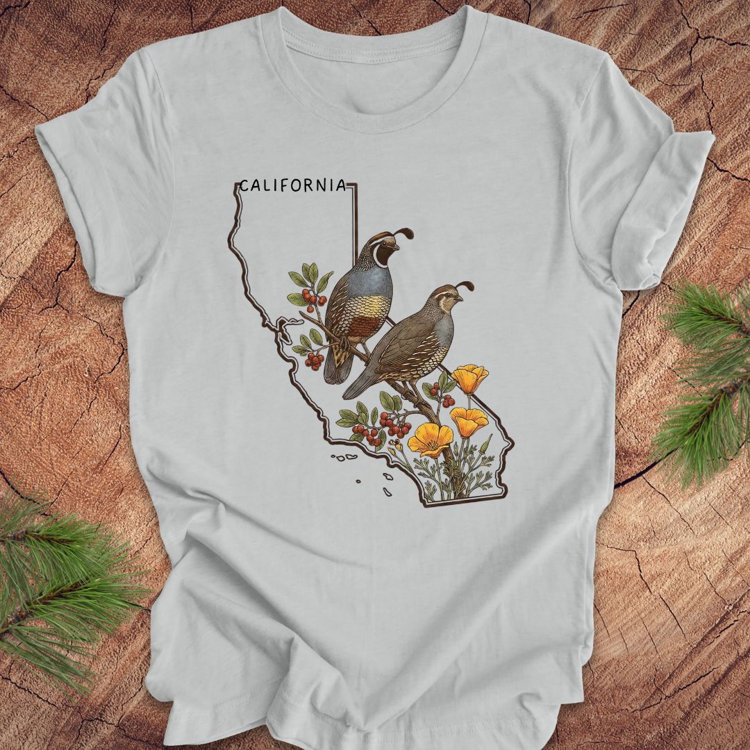Gray t-shirt with California map design featuring quails and flowers on a wooden surface.