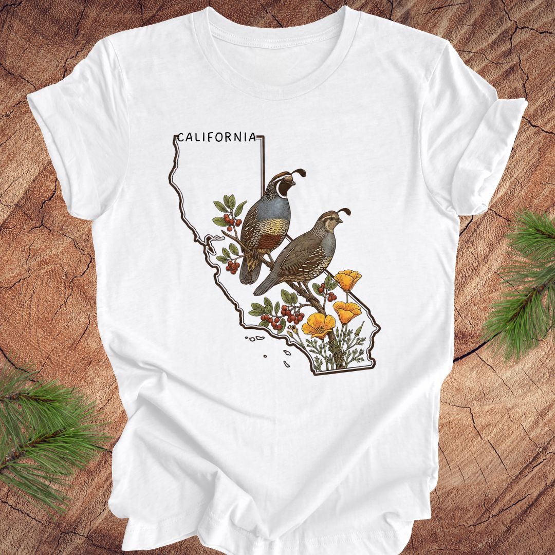 White t-shirt with California map design featuring quails and flowers on a wooden surface.