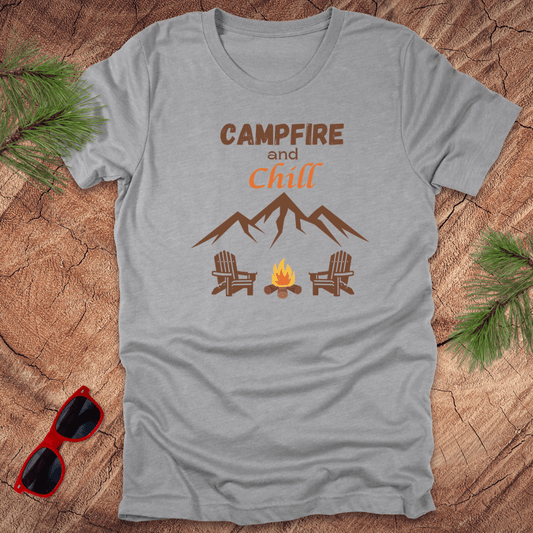 A grey t-shirt with the text 'CAMPFIRE and Chill' printed on the front, featuring an illustration of mountains, a campfire, and two chairs.