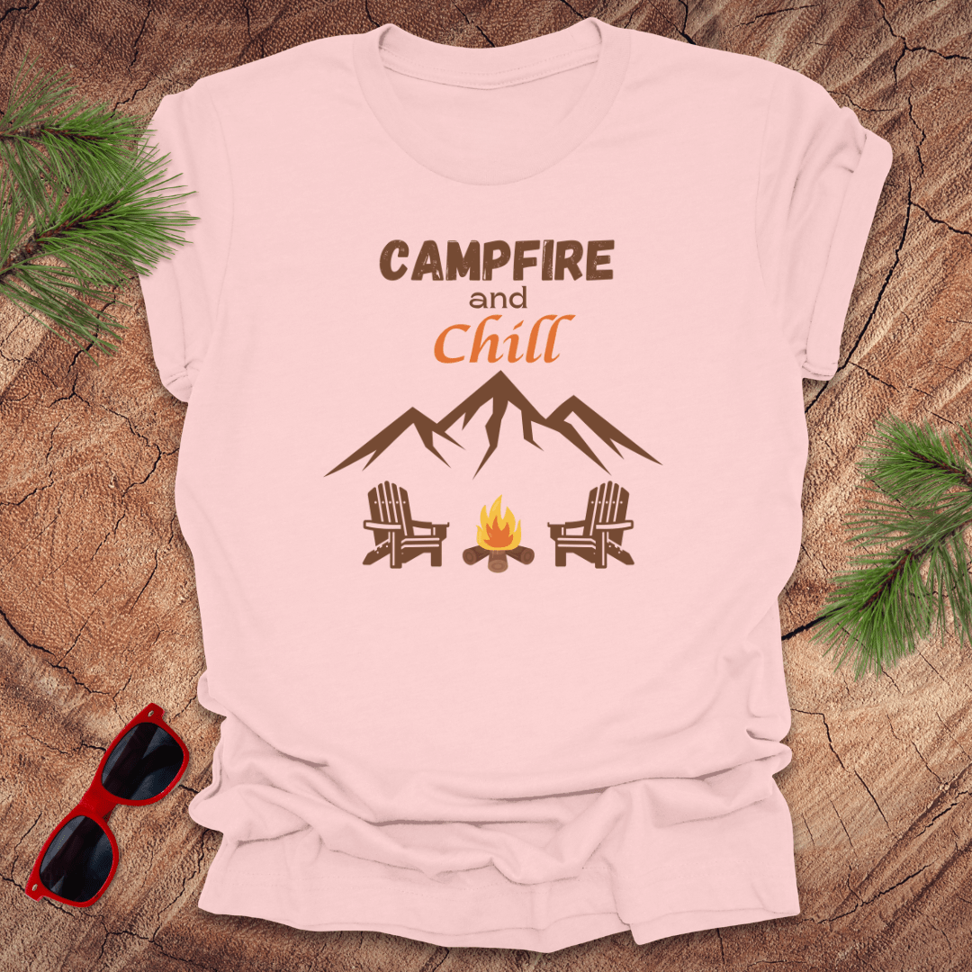 A pink t-shirt with the text 'CAMPFIRE and Chill' printed on the front, featuring an illustration of mountains, a campfire, and two chairs.