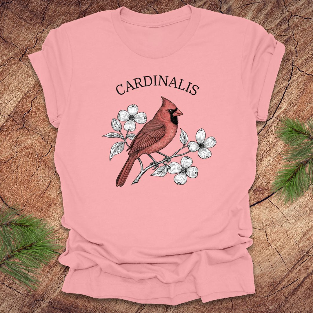 Pink t-shirt with a red cardinal bird design and scientific name text on a wooden surface