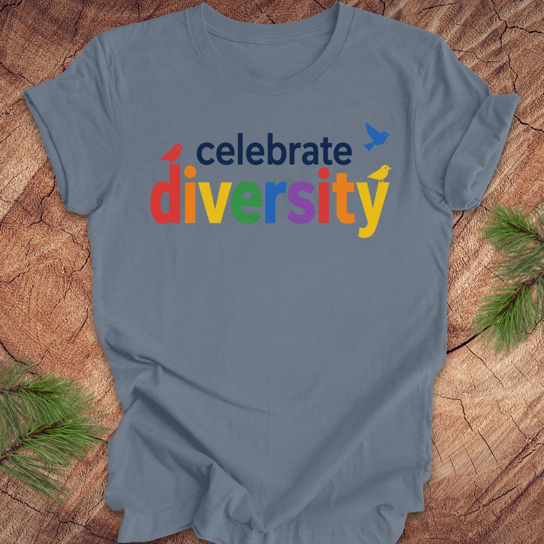 Blue t-shirt with 'celebrate diversity' in colorful letters on a wooden surface.