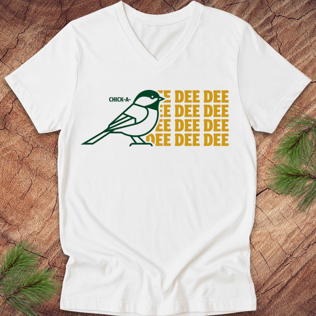 White v-neck t-shirt with a green chickadee graphic and yellow text on a wooden surface.