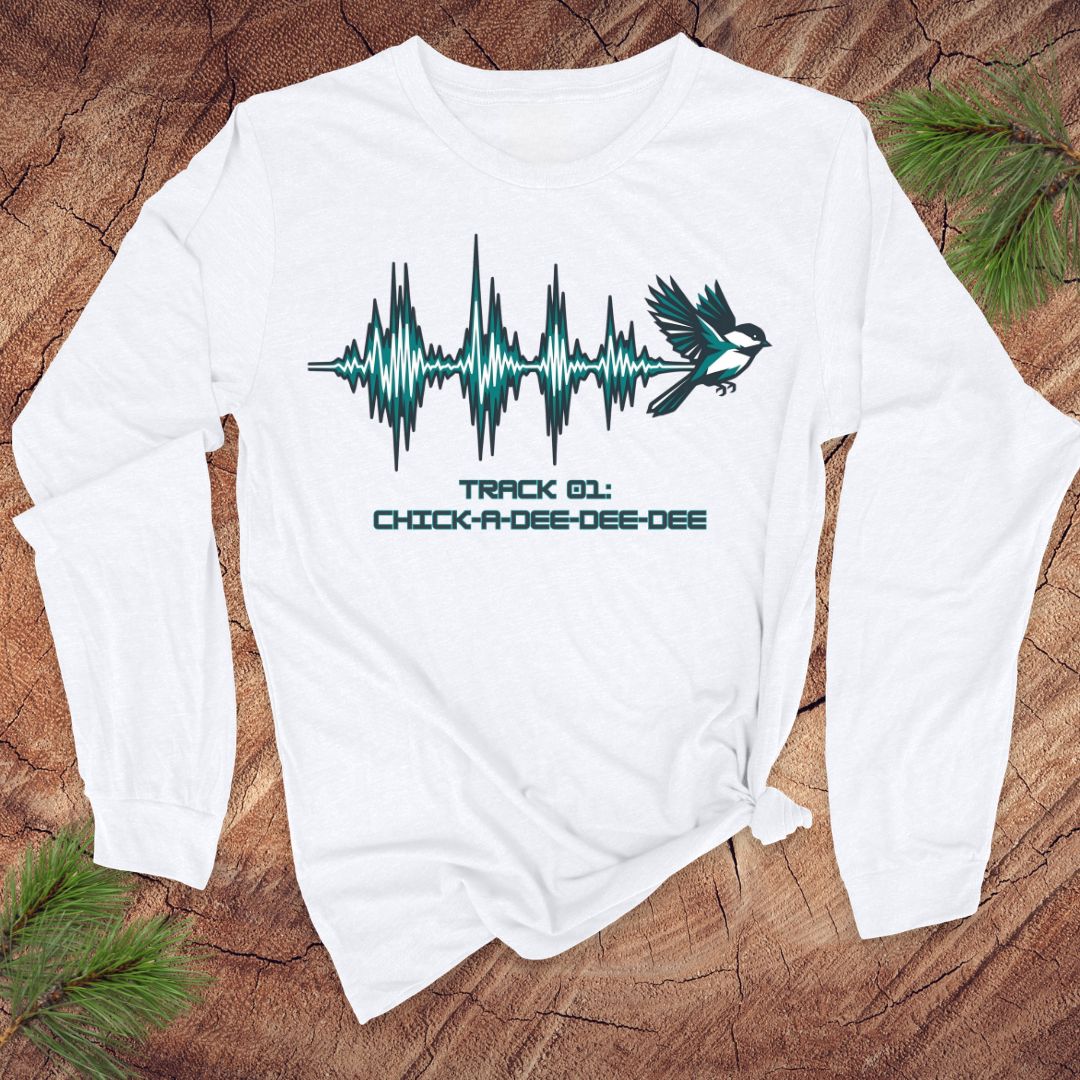 White long-sleeve shirt with a chickadee and sound wave design on a wooden surface