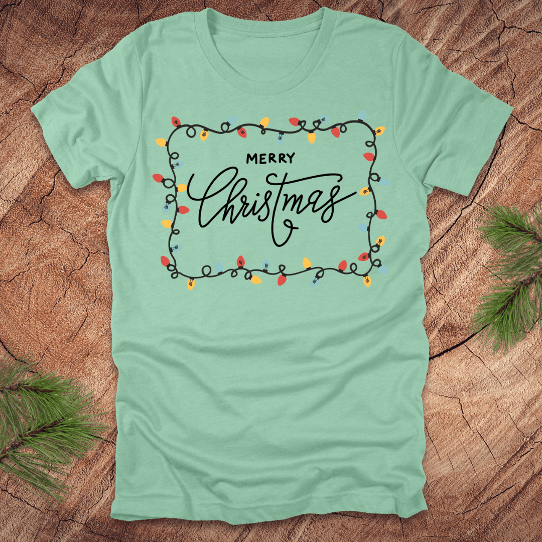 Mint Green t-shirt with christmas lights graphic and 'Merry Christmas' design on a wooden surface