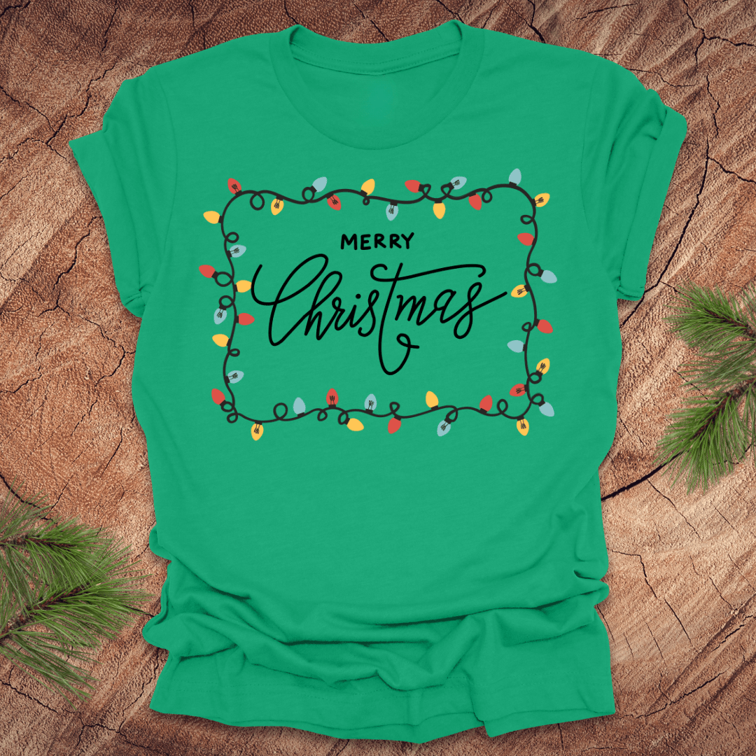 Green t-shirt with christmas lights graphic and 'Merry Christmas' design on a wooden surface