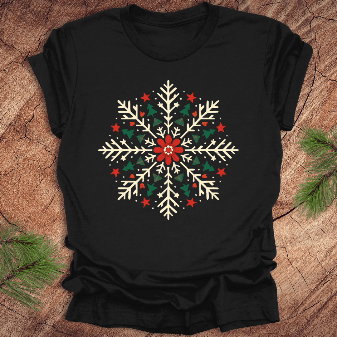 Black t-shirt with a colorful snowflake design on a wooden surface with pine branches.