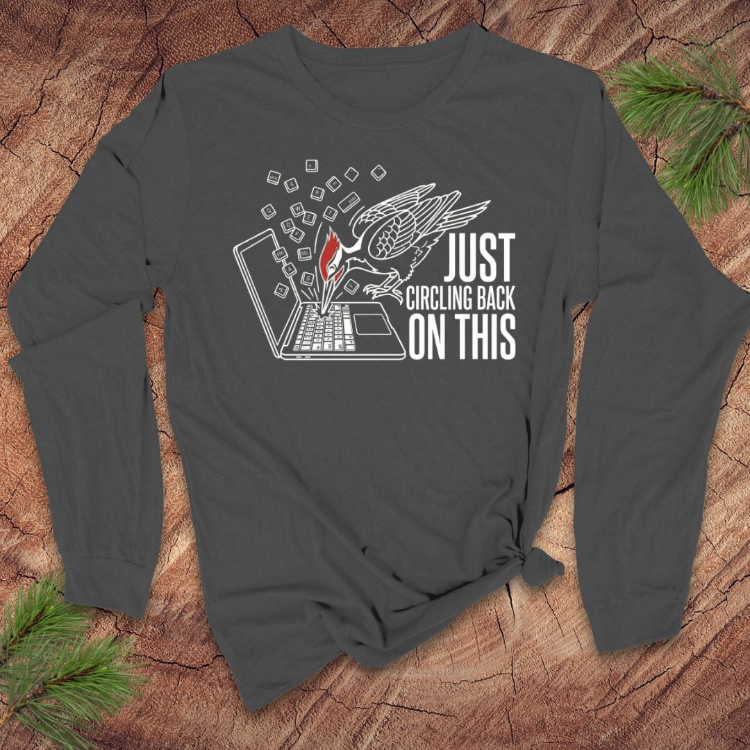 Gray long-sleeve shirt with graphic design and text on a wooden surface