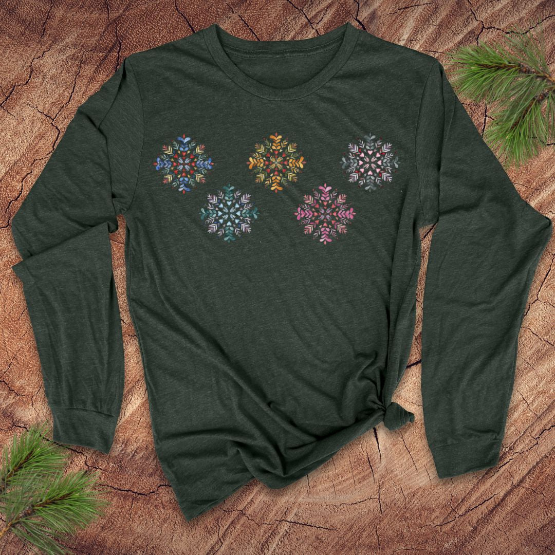 Green long-sleeve shirt with colorful folk art snowflake designs on a wooden surface