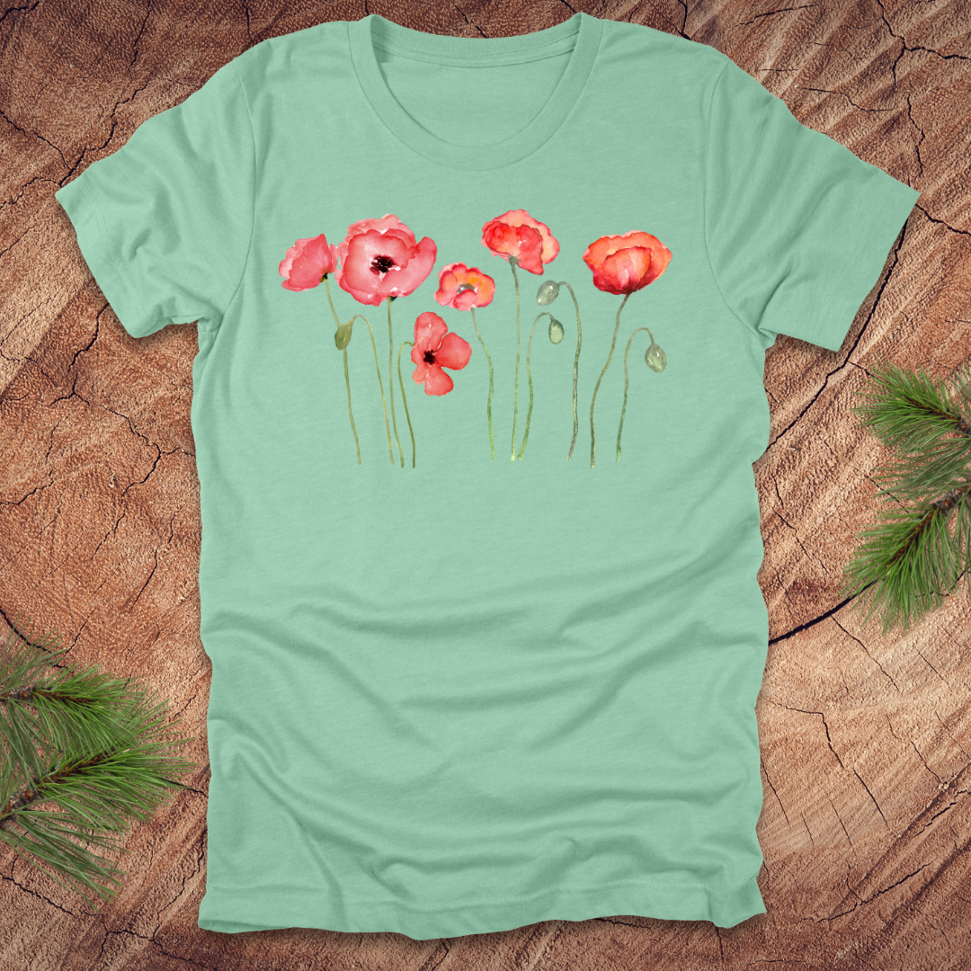Mint green t-shirt with red poppy design on a wooden surface
