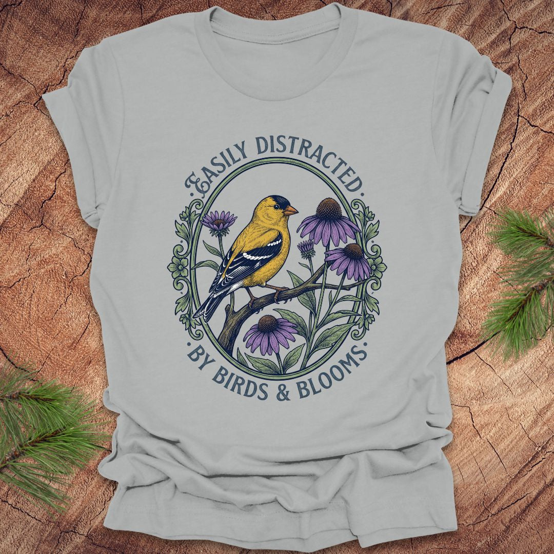 Light gray t-shirt with a bird and floral design on a wooden surface