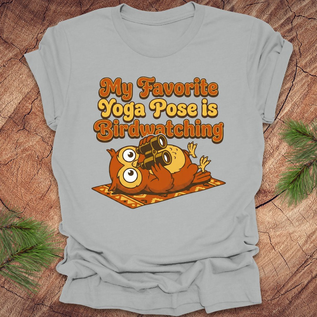 Light gray t-shirt with owl design and text 'My Favorite Yoga Pose is Birdwatching' on a wooden surface.