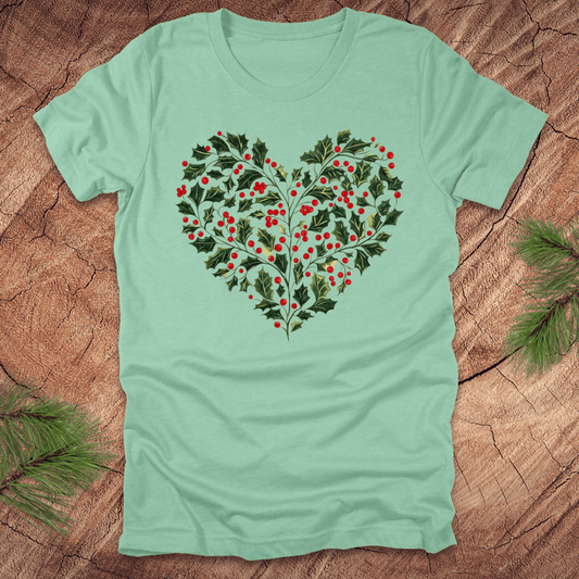 Mint green t-shirt with a heart-shaped holly design on a wooden surface.