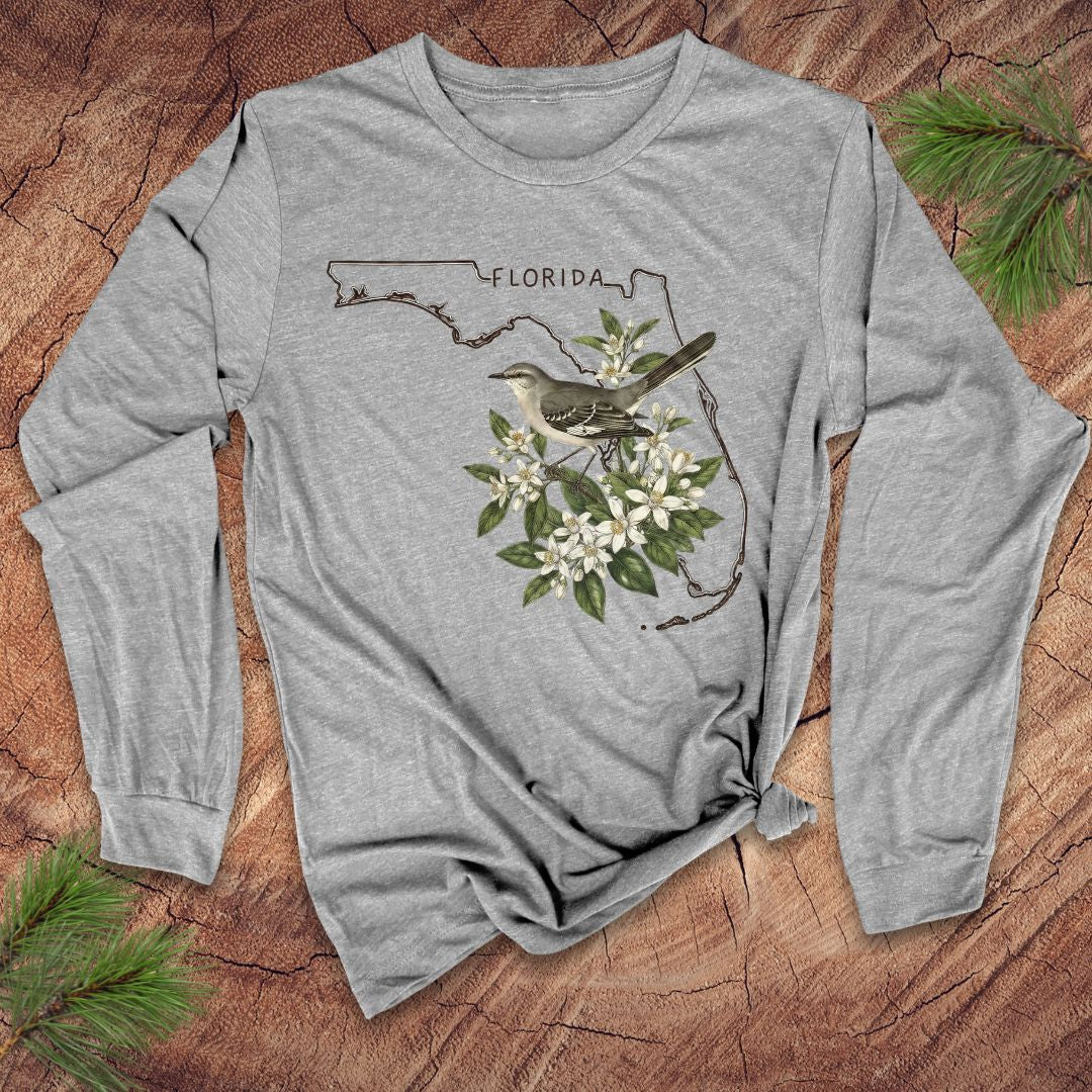 Gray long-sleeve shirt with Florida outline and mockingbird design on a wooden surface