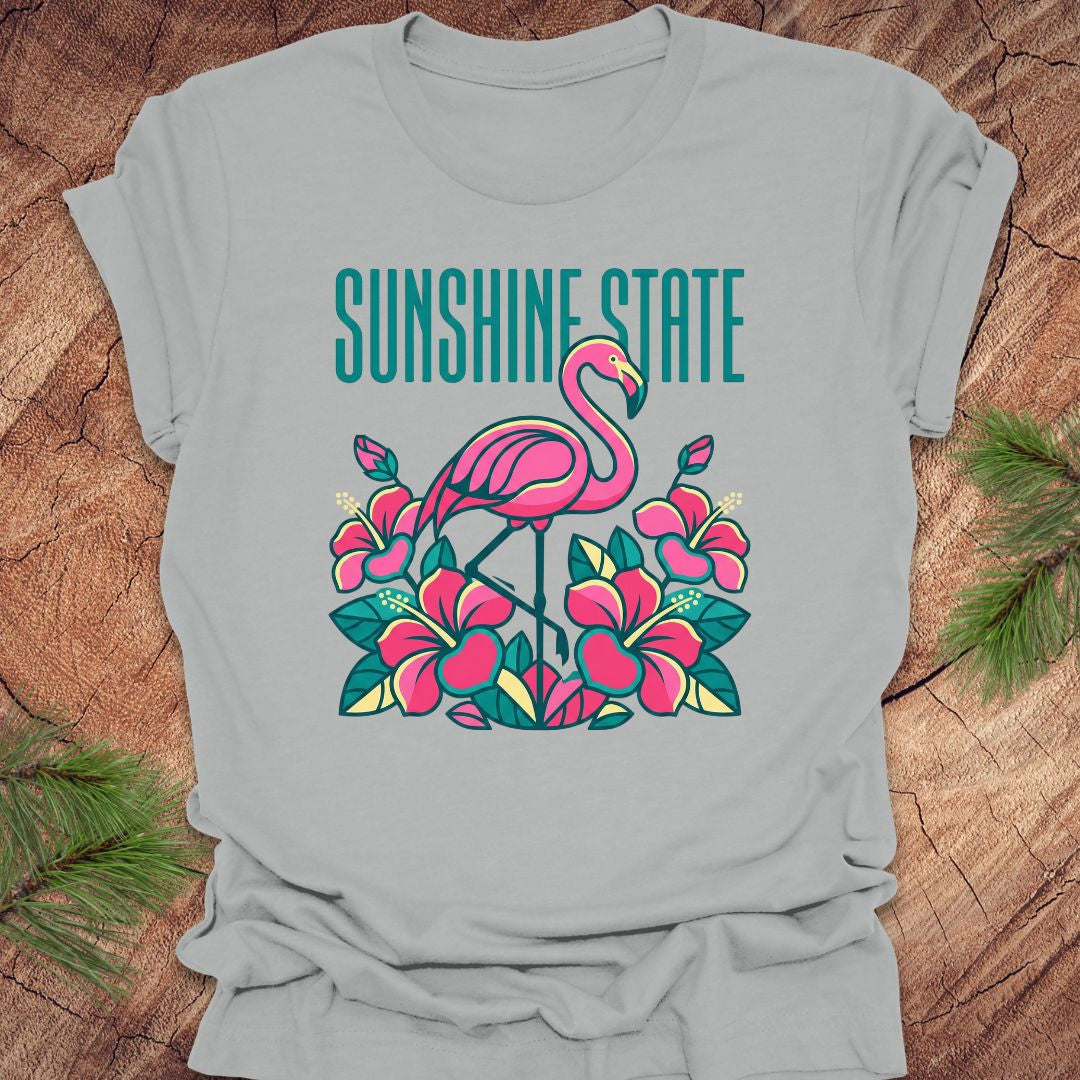 Gray t-shirt with a pink flamingo and floral design on a wooden surface