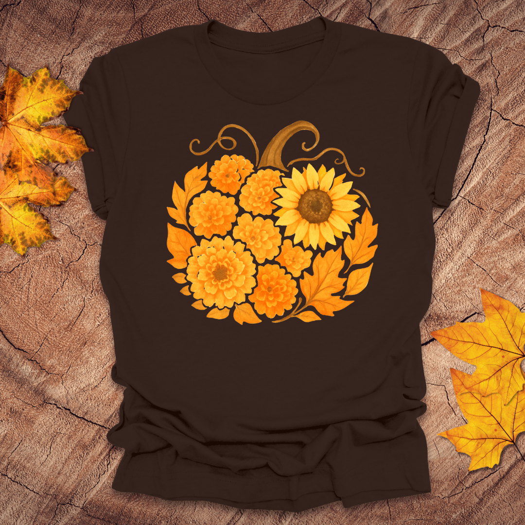 Brown t-shirt with a pumpkin design made of sunflowers on a textured surface with autumn leaves.