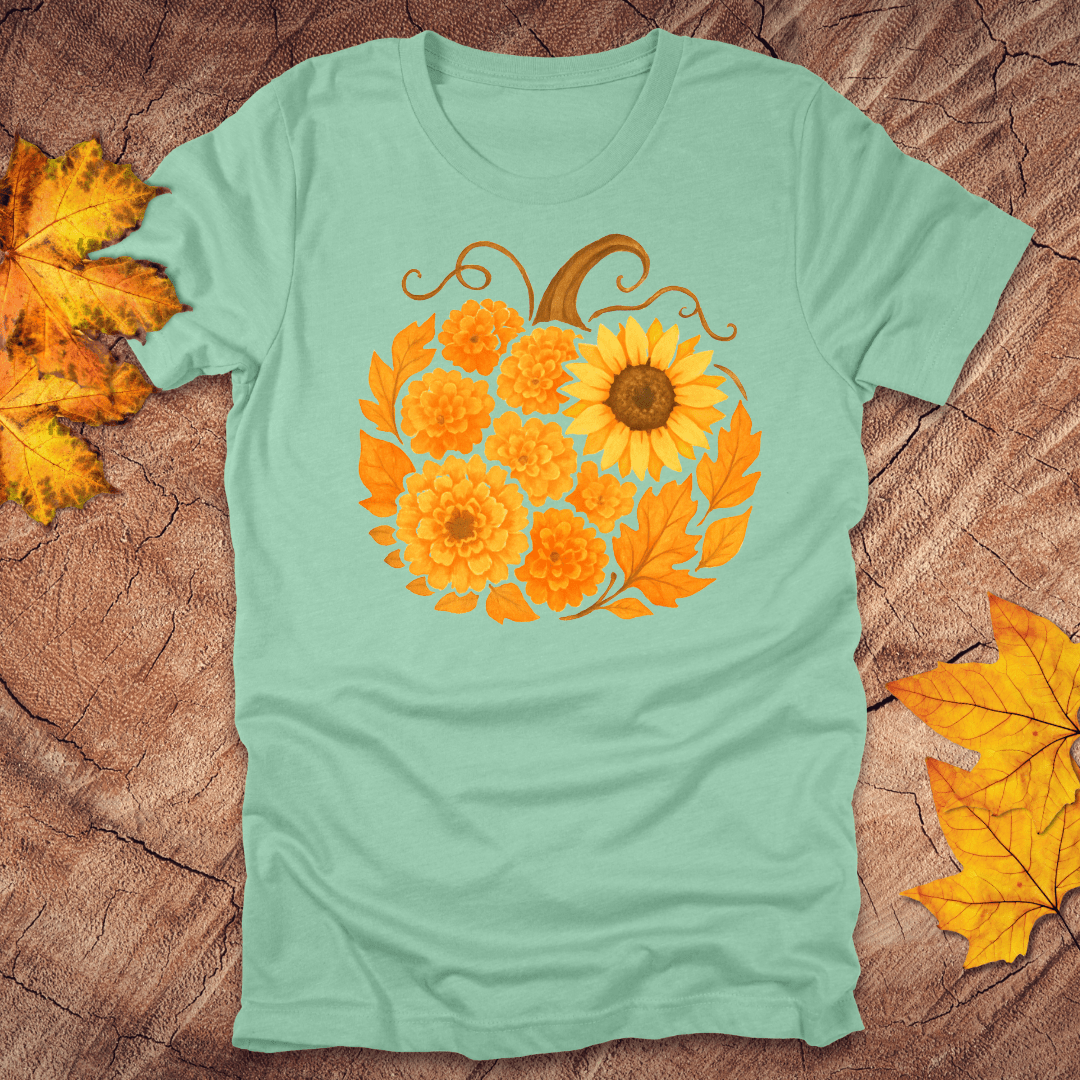 heather mint t-shirt with a sunflower design on a wooden surface with fall leaves.