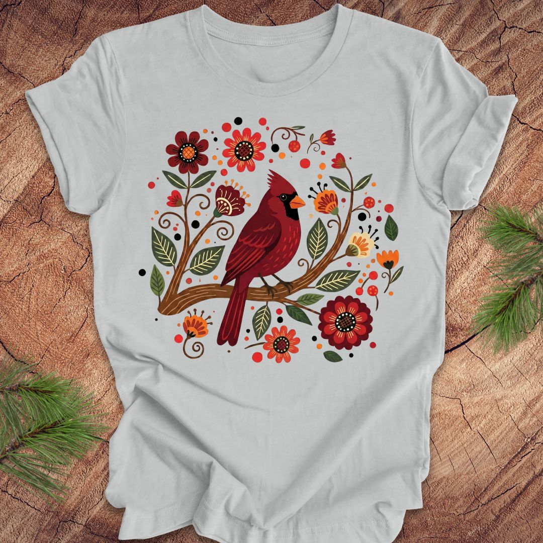Silver t-shirt with a red cardinal and floral design on a wooden surface