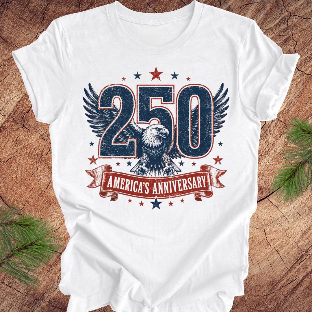 White t-shirt with '250 America's Anniversary' design featuring an eagle on a wooden surface.