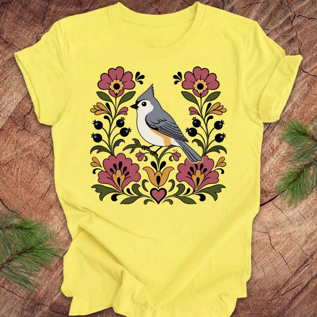 Yellow t-shirt with a titmouse and floral design on a wooden surface