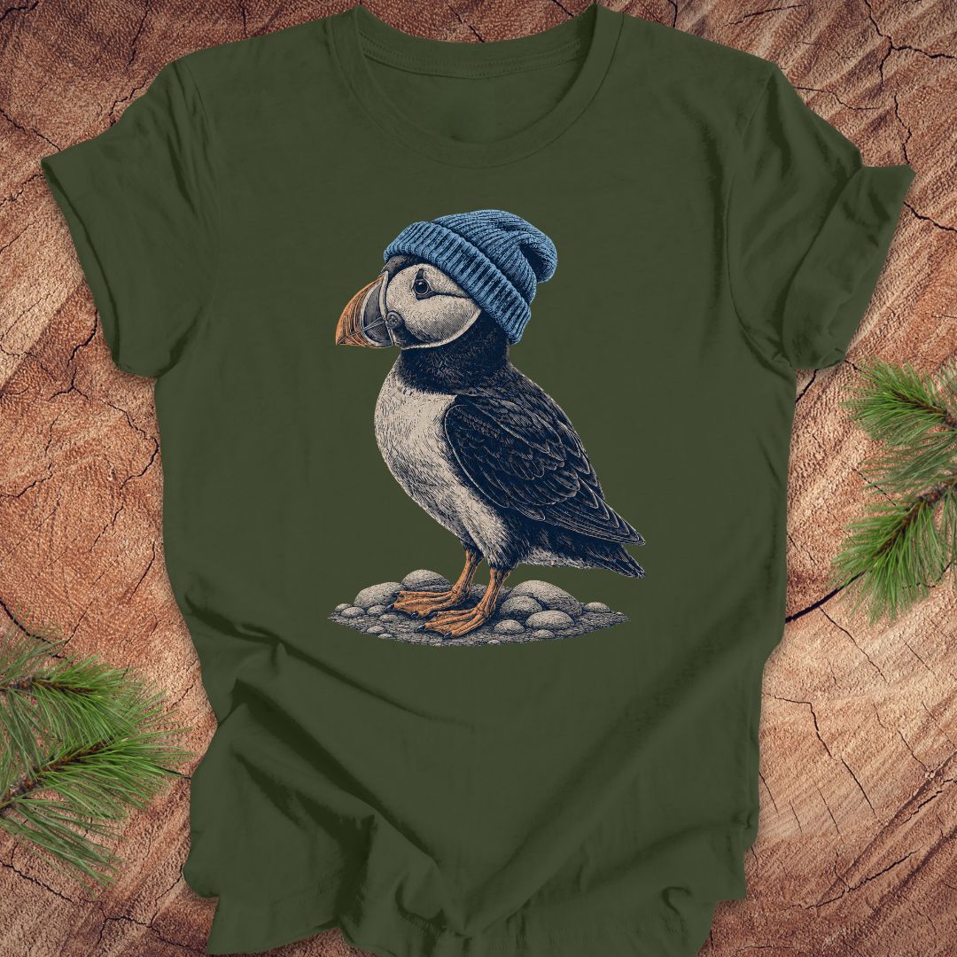 Green t-shirt with a puffin wearing a blue beanie on a wooden surface.