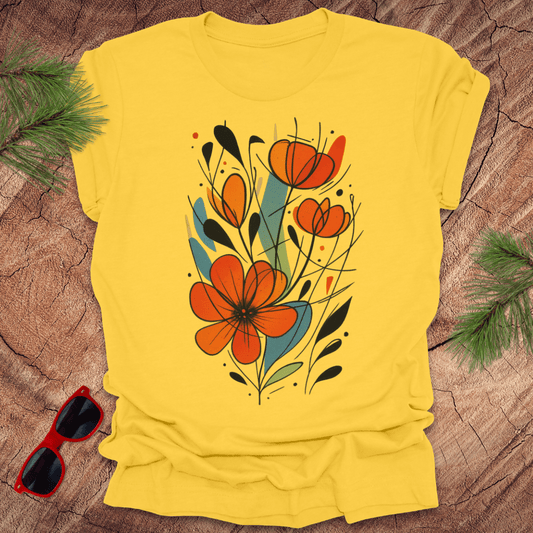 Yellow t-shirt with orange floral design on a wooden surface with sunglasses and greenery.