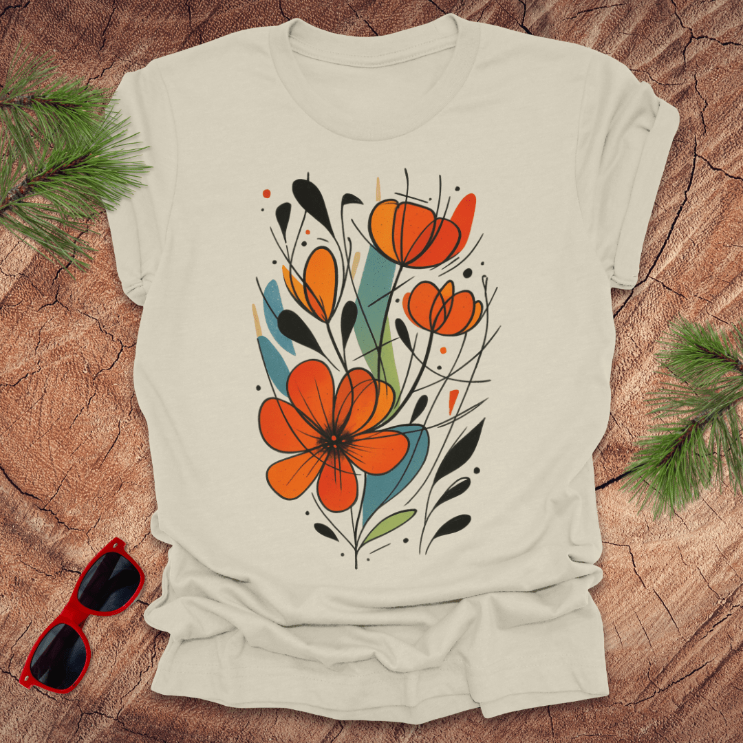 Beige t-shirt with orange floral design on a wooden surface with sunglasses and greenery.