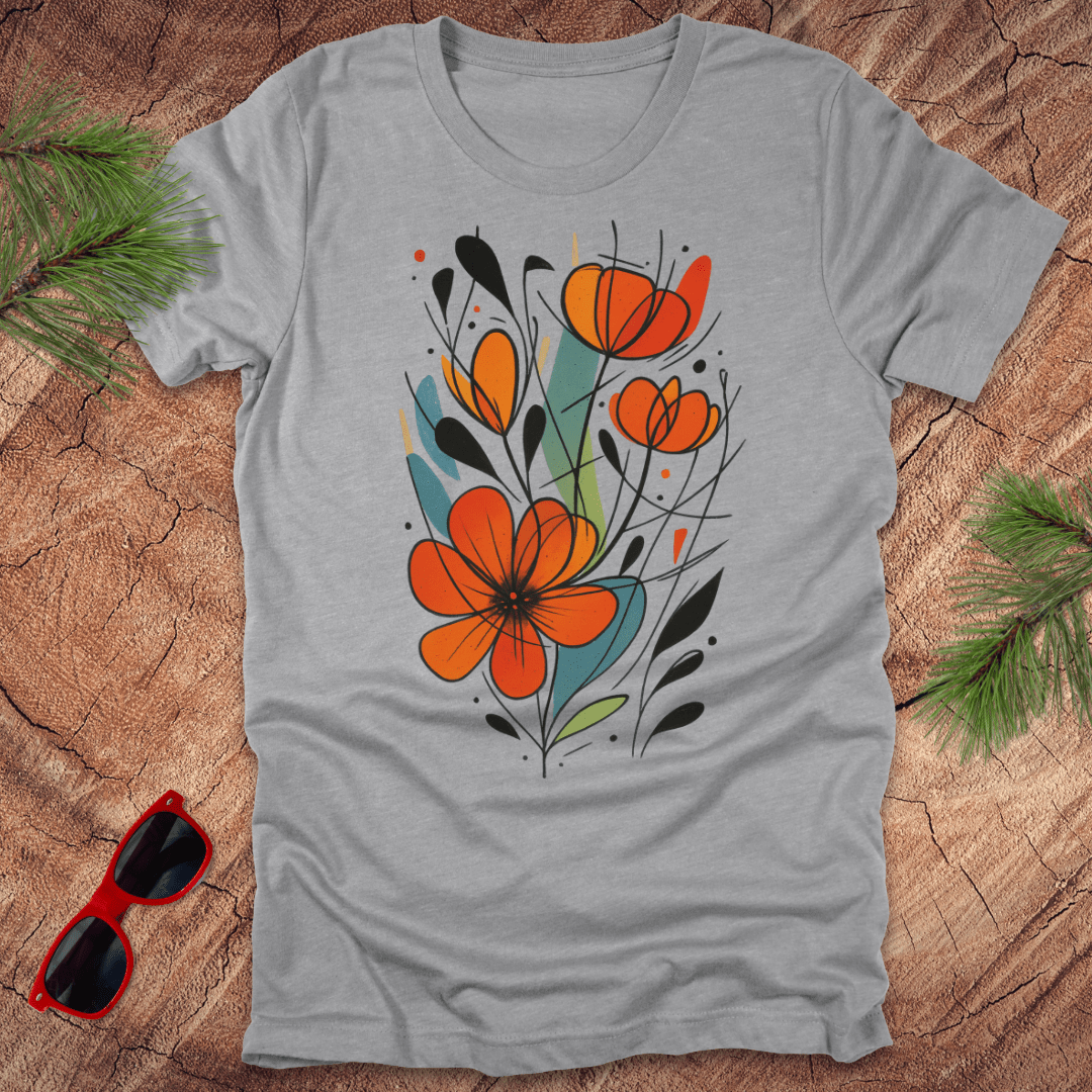 Gray t-shirt with orange floral design on a wooden surface with sunglasses and greenery.