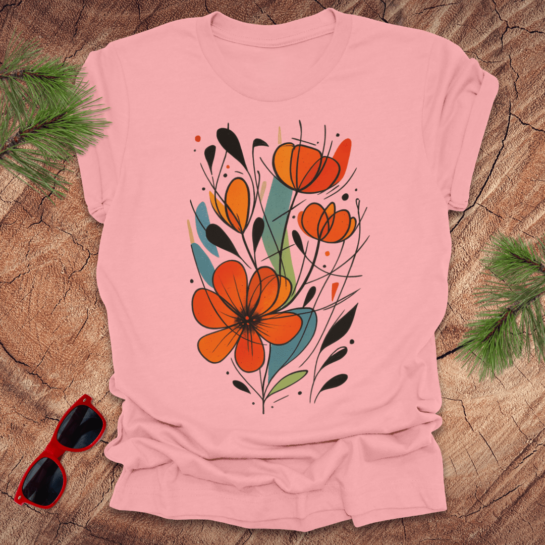 Pink t-shirt with orange floral design on a wooden surface with sunglasses and greenery.