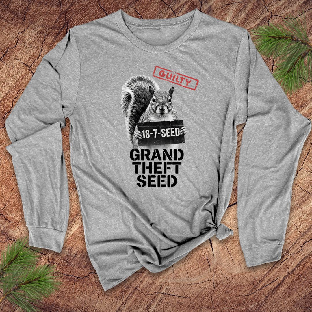 Gray long-sleeve shirt with a graphic of a squirrel holding a seed packet and text, 'guilty. grand theft seed' on a wooden surface.