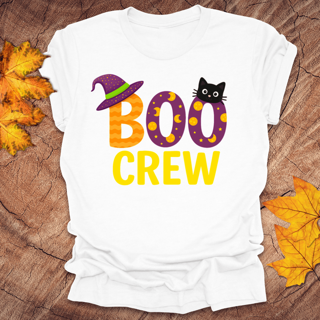 White t-shirt with 'BOO CREW' text and Halloween graphics on a wooden surface with fall leaves.