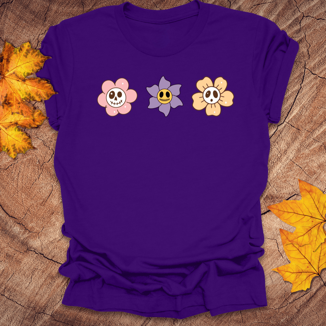 Purple t-shirt with cartoon flower designs on a wooden surface with autumn leaves.