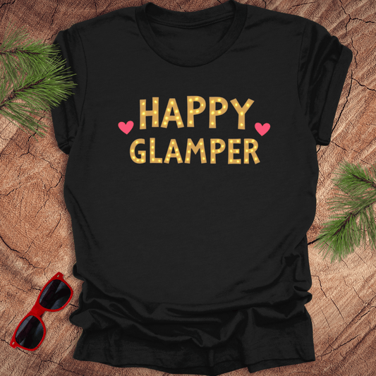Black t-shirt with 'Happy Glamper' text on a wooden surface with sunglasses and pine branches.