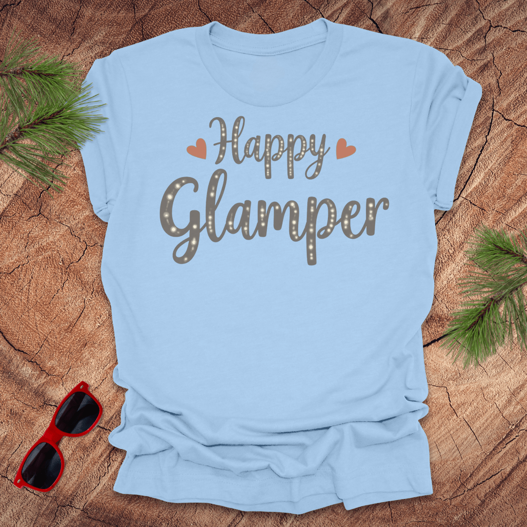 Light blue t-shirt with 'Happy Glamper' text on a wooden surface with sunglasses and greenery.