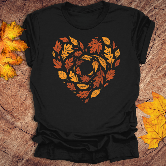 Black t-shirt with autumn leaf design in the shape of a heart on a wooden surface with sunglasses and greenery.