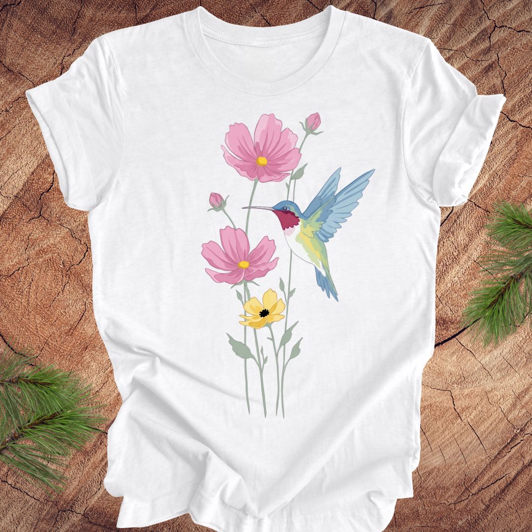 White t-shirt with floral and hummingbird design on a wooden surface