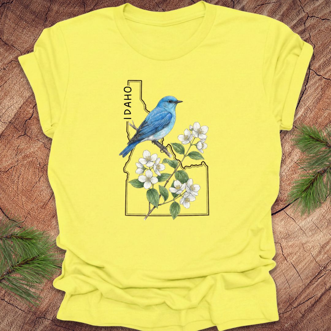 Yellow t-shirt with a blue bird and white flowers design on a wooden surface