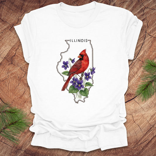 White t-shirt with Illinois state outline and state bird and flower cardinal and violets design on a wooden surface