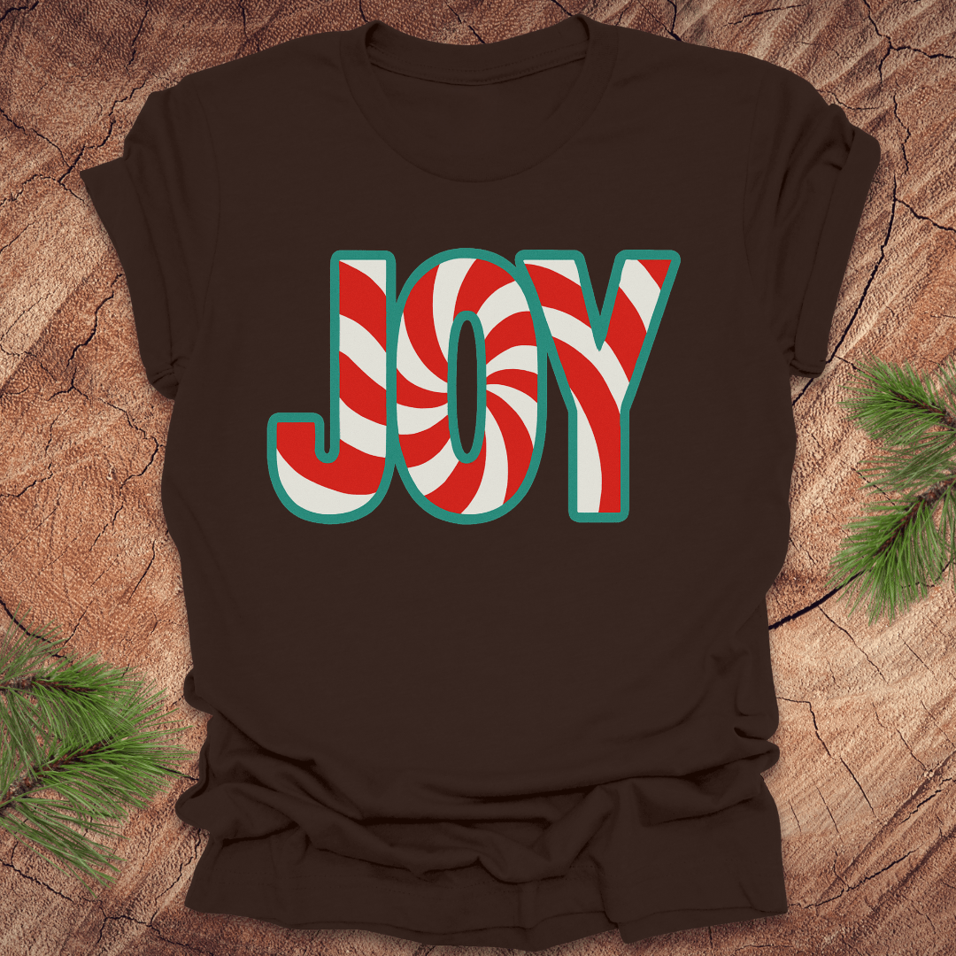 Brown t-shirt with the text, "JOY" in a red and white pattern on a wood background