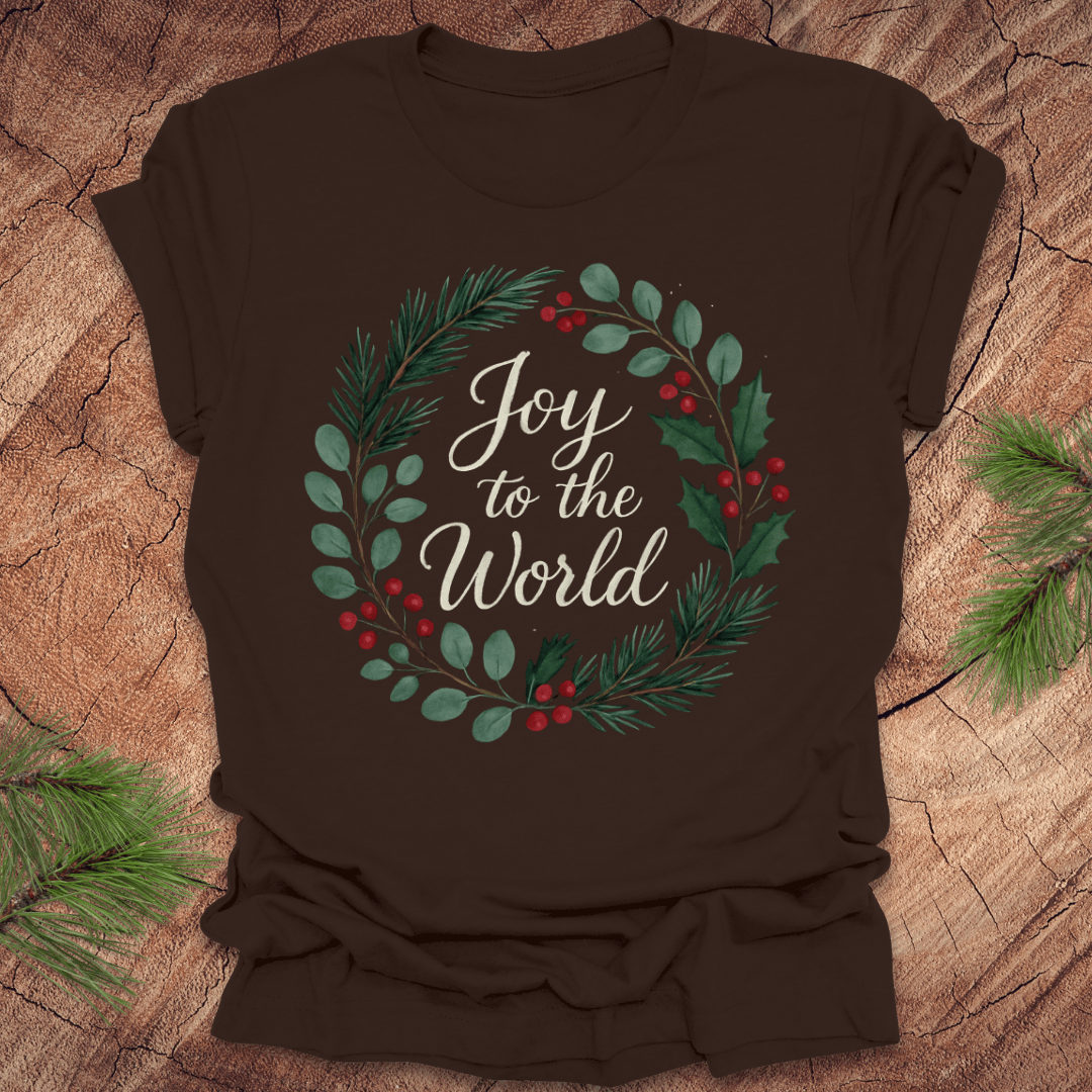 Brown t-shirt with wreath and text, 'Joy to the World' design on a wooden surface